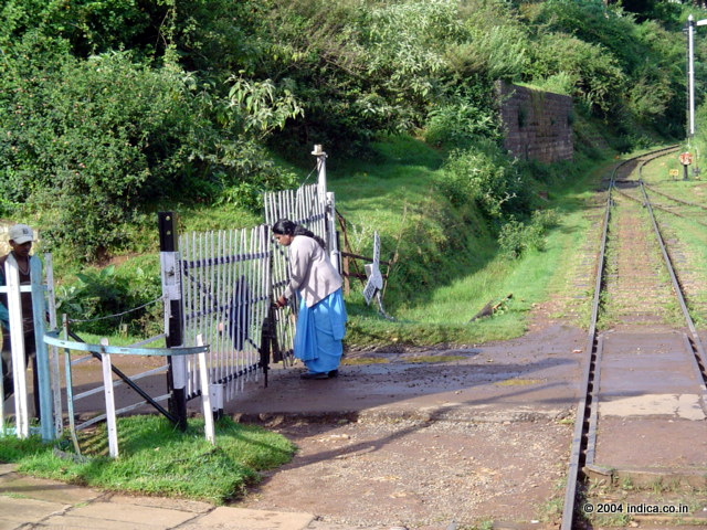 Guard closes the gate, before the train leaves the station. This is on the way to Ooty by the Nilgiri Mountain Railway.