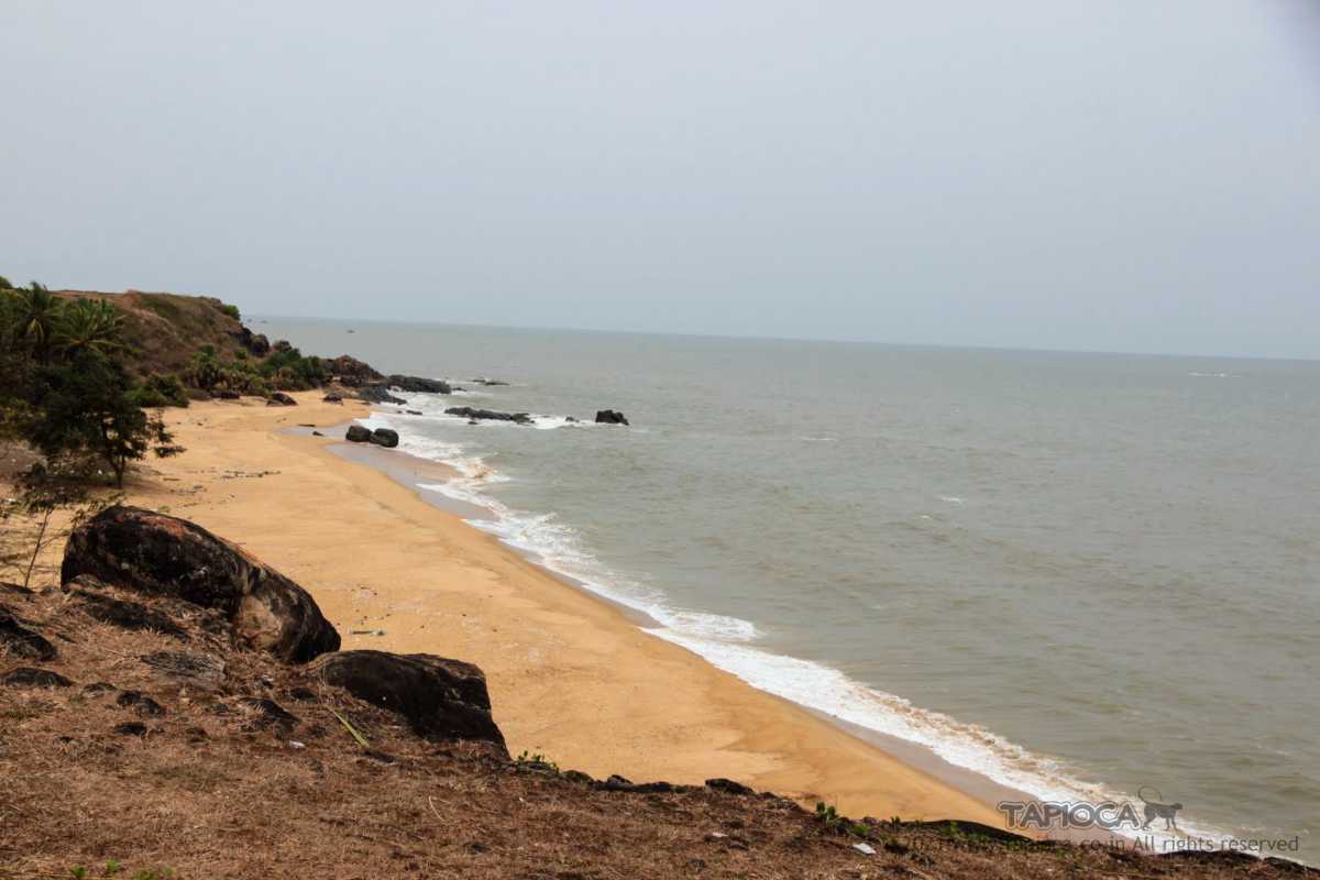 The tiny secluded beach sandwiched between two cliffs. Seen in the farther side is the Bekal Cliff. Photograph taken from the hill on the edges of the Kappil River.